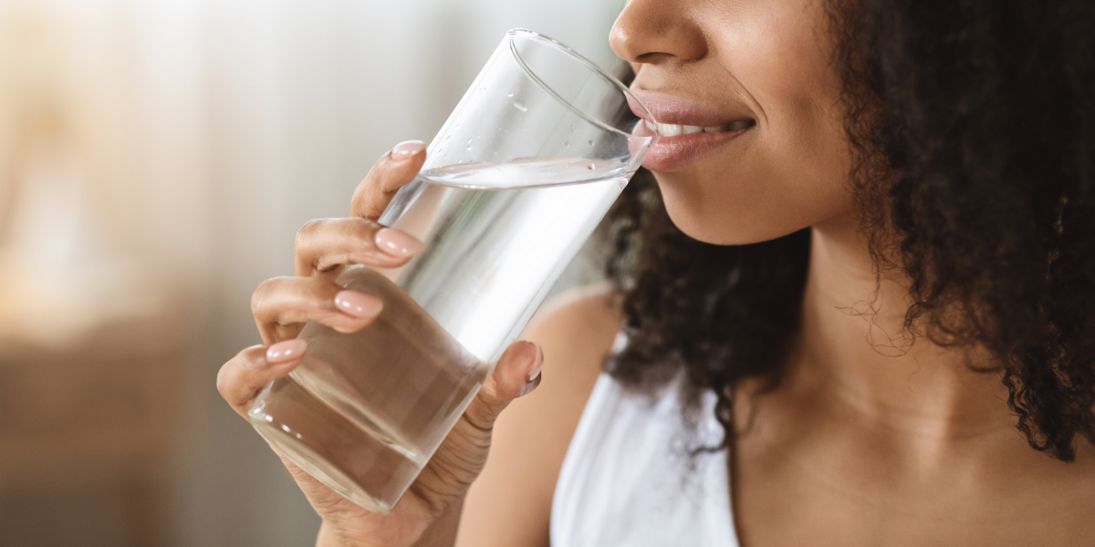 woman in a white shirt drinking clean water out of a drinking glass
